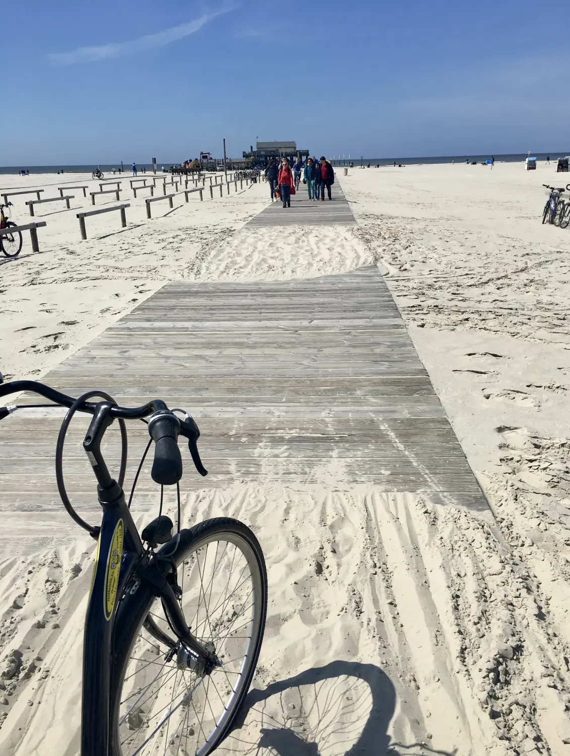 Blick über einen Fahrradlenker auf einen Steg Richtung Strand